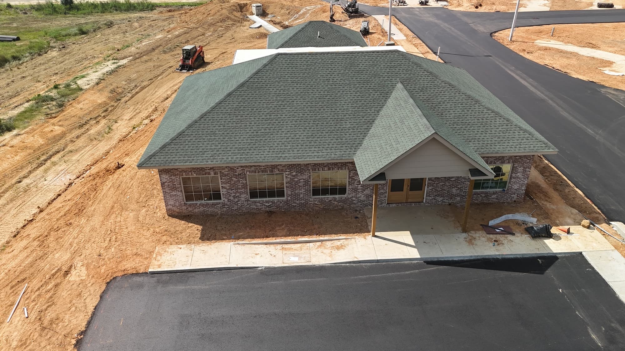 Aerial view of the brick park office and bathhouse with its green shingle roof and covered porch